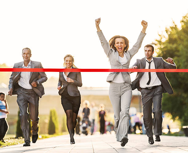 Happy businesswoman crossing finish line during race business competition